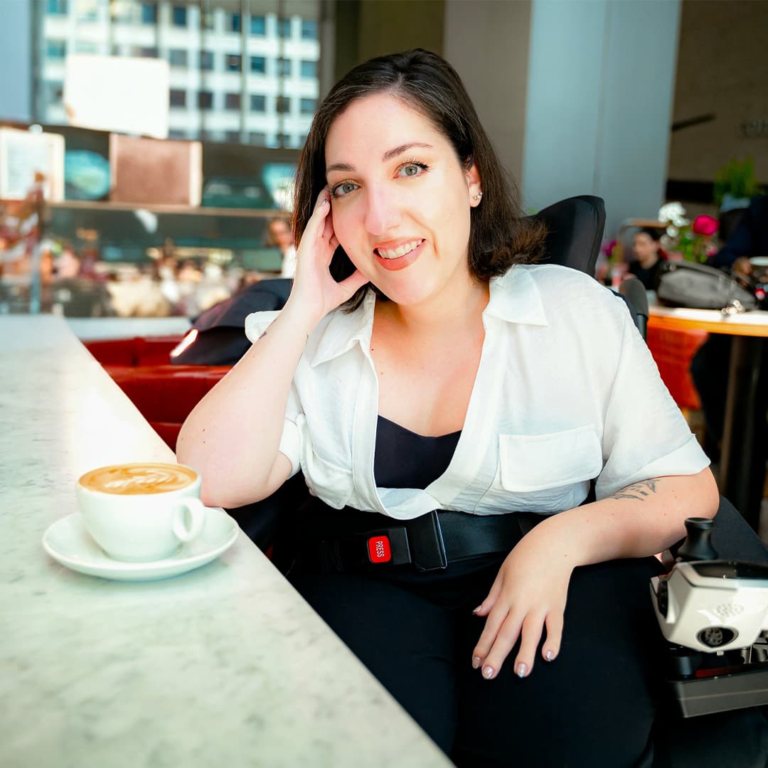 Jessica Oddi in her wheelchair seated at a coffee shop counter