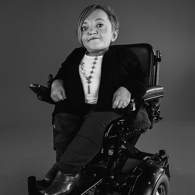 Stella Young in her wheelchair in a stylized black and white portrait photo